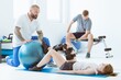 © Photographee.eu - Pretty patient sitting on the blue mat in the gym and training with the ball