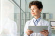 © pressmaster - Smiling attractive laboratory worker with curly hair satisfied with research results using digital tablet