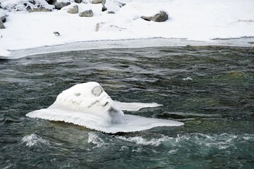 Sticker - Small snow covered rock in a creek in winter