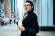 © BullRun - Half length portrait of confident proud ceo expert dressed in elegant apparel looking at camera while standing on Manhattan street during work break for coffee, attractive businesswoman outdoors