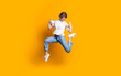 © Strelciuc - Jumping caucasian woman in jeans and white t-shirt smiling and advertising something on a yellow studio wall
