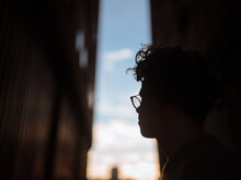 Silhouette Of Young Guy Framed Between Buildings Looking Out Towards Sky.