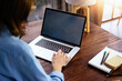 © Rymden - Mockup image of a woman using laptop with blank screen on wooden table