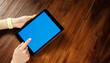 © Rymden - Mockup image of a woman using digital tablet with blank screen on wooden table. Close up photo of female hands holding device vertically