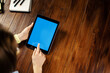 © Rymden - Mockup image of a woman using digital tablet with blank screen on wooden table. Close up photo of female hands holding device vertically