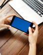 © Rymden - Close up photo of female hands holding smartphone horizontally. Mockup concept with copy space and blank screen