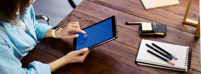 Mockup image of a woman using digital tablet with blank screen on wooden table. Close up photo of female hands holding device vertically