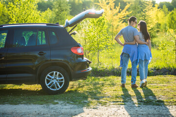 Back of woman hugging man and looking view in sunrise. Couple travel in holiday by hatchback car. Love