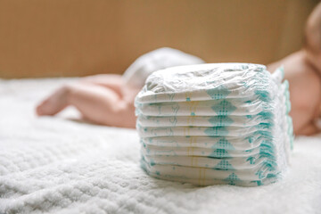 A baby in a diaper at the age of two months and a stack of diapers. How to choose baby diapers