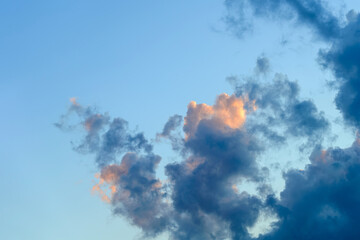 Wall Mural - golden blue evening cloud on a blue sky background. cloud is partially colored with golden pink by t