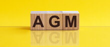 AGM - Annual General Meeting - Acronym On Wooden Cubes On Yellow Backround. Business Concept.
