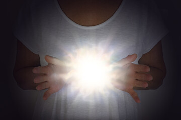 Wall Mural - Healing Energy Phenomenon - female in white tunic with hands apart at chest level with a bright shining white orb light between 
