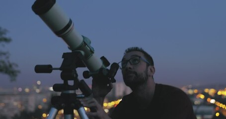 Wall Mural - astronomer with a telescope watching at the stars and moon with blurred city lights in the backgroun