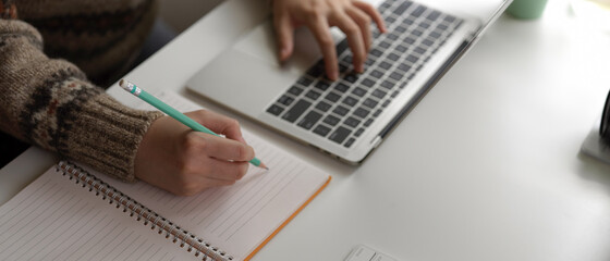 Female university student preparing informations for her presentation with laptop and blank notebook