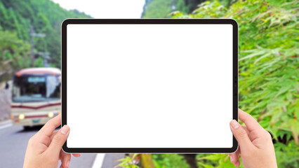 Two hands holding white screen mockup tablet computer, bus and road in Japan countryside .