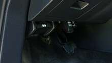 OBD2 car scanner tool plug into diagnostic port under steering wheel dashboard.