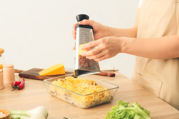 Woman preparing tasty pasta in baking dish on table