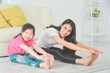 © gamelover - Asian mother and daughter practicing yoga together at home.Mother and child sitting and stretching their body on the floor.