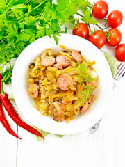 Poster - Cabbage stew with sausages in white plate on board top