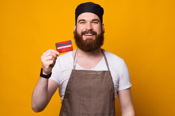 Photo of young happy Chef showing red credit card while standing