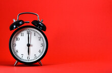 An Old Alarm Clock Showing 6 O'clock On Red Background