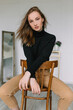 © Hanna Chayka - girl woman model sitting on a chair in a stylish room white in brown trousers