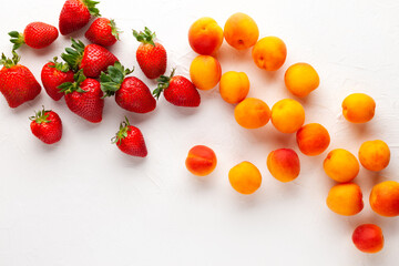 Wall Mural - Fresh organic apricots and strawberry on white background. Vegetarian, clean and healthy eating concept. Flat lay, copy space.