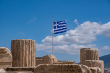 Athens, Greece. Greek Flag And Ancient Column Remains In Acropolis Against Blue Sky Background