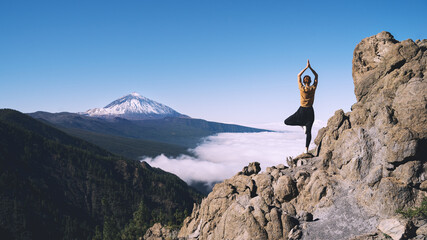 Woman doing yoga and meditating on background of natural landscape