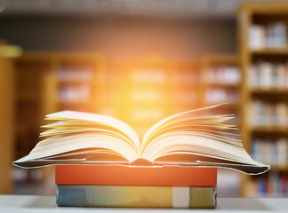 Open Book on wood table and blurred bookshelf in the library, education background, back to school concept.