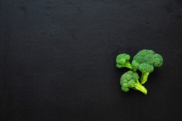 Healthy green organic raw broccoli florets on black background