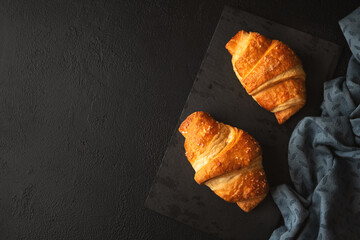 Wall Mural - Fresh golden croissants on dark slate board. Top view