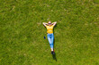 © F8  \ Suport Ukraine - Aerial view. Young girl lying and resting on lawn on sunny day in park on grass. Above view. Woman on grass in meadow. Top view
