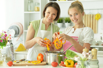 Wall Mural - Portrait of cute little girl with mother cooking