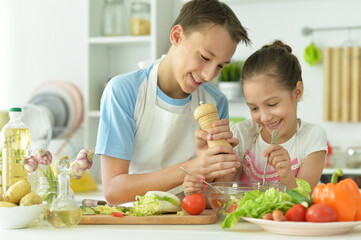 Wall Mural - Portrait of cute brother and sister cooking together in kitchen