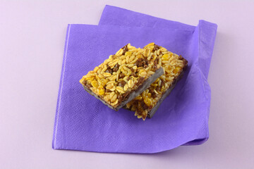 Sticker - Dark chocolate and rice candy bar snack halves on purple napkin on lavender background