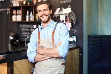 Wall Mural - Male business owner behind the counter of a coffee shop with crossed arms, looking at camera.