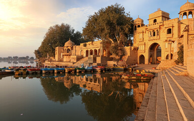 Fototapete - Gadi Sagar (Gadisar) lake Jaisalmer Rajasthan India with tourist boats and ancient architecture at sunrise.	