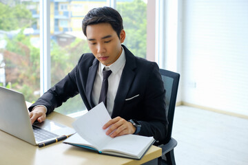  Young businessman sitting and working on desk and using computer laptop connecting internet and Looking at the notebook at office, employee or company ceo using online apps,Busy work