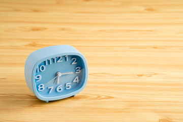 Alarm clock on textured wooden background.