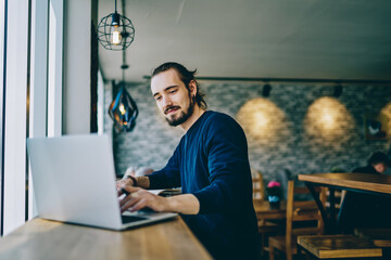 Caucasian freelancer searching web information during remote programming on modern laptop computer, millennial male user watching online tutorial during distance job with project via netbook