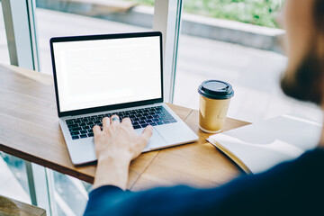 Cropped image of male hand browsing websites via application on mockup laptop computer, skilled man working remotely with program for software update connected to 4g wireless internet on blank netbook