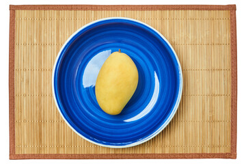 Wall Mural - yellow mango on a blue plate on a cane serving mat