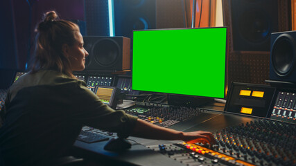 Fototapete - Portrait of Stylish Female Audio Engineer / Producer Working in Music Record Studio, Uses Green Screen Computer Display, Mixer Board, Control Desk to Create New Song. Creative Artist Musician 