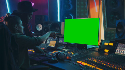 Wall Mural - Producer and Audio Engineer Working together in Music Record Studio on a New Album, Use Green Screen Computer, Control Desk for Mixing and Creating Hit Song. Artist and Musician Collaboration