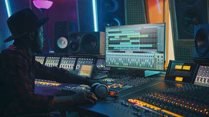Fototapete - Stylish Audio Engineer Working in Music Recording Studio, Uses Mixing Board and Software to Create Modern Hit Song. Portrait of Black Artist Musician Working at Control Desk