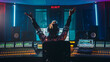 Artist, Musician, Audio Engineer, Producer in Music Record Studio, Uses Control Desk with Computer Screen showing Software UI with Song Playing. Celebrates Success with Raised Hands, Dances. Back View