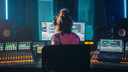 Fototapete - Artist, Musician, Audio Engineer, Producer in Music Record Studio, Uses Control Desk with Computer Screen showing Software UI with Song Playing. Dances. Back View