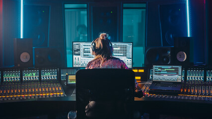 Poster - Artist, Musician, Audio Engineer, Producer in Music Record Studio, Uses Control Desk with Computer Screen showing Software UI with Song Playing. Dances. Back View