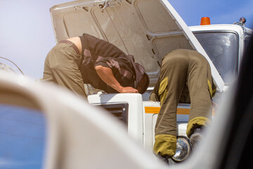 Wall Mural - men repairing a truck with manual labor under the open hood with a hand tool, engine accident on a long journey